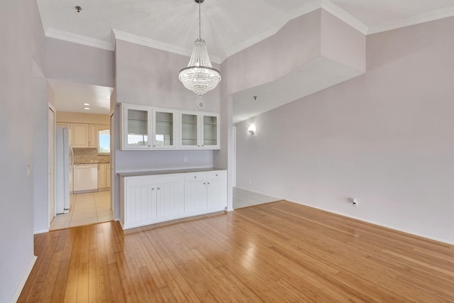 unfurnished living room with a notable chandelier, light tile patterned floors, and ornamental molding