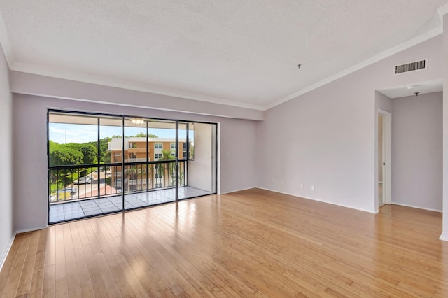 spare room featuring crown molding, light hardwood / wood-style flooring, a textured ceiling, and lofted ceiling