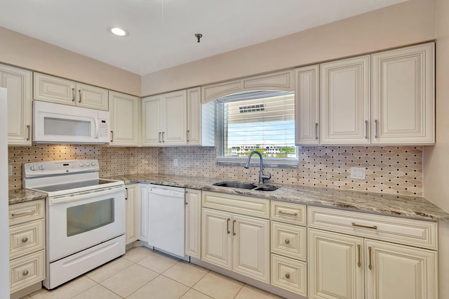 kitchen featuring white appliances, light tile patterned floors, a sink, light stone countertops, and backsplash