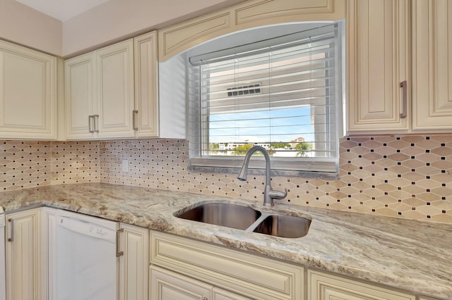 kitchen featuring cream cabinetry, sink, light stone countertops, and dishwashing machine