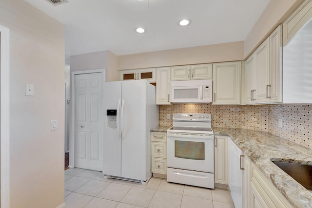 kitchen featuring light tile patterned flooring, tasteful backsplash, light stone counters, and white appliances