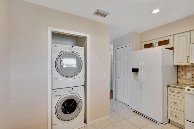 laundry room featuring stacked washing maching and dryer and light tile patterned floors