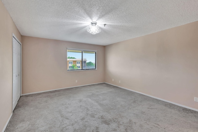 carpeted empty room featuring a textured ceiling