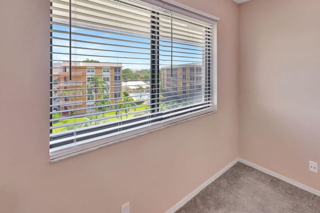 carpeted spare room featuring baseboards