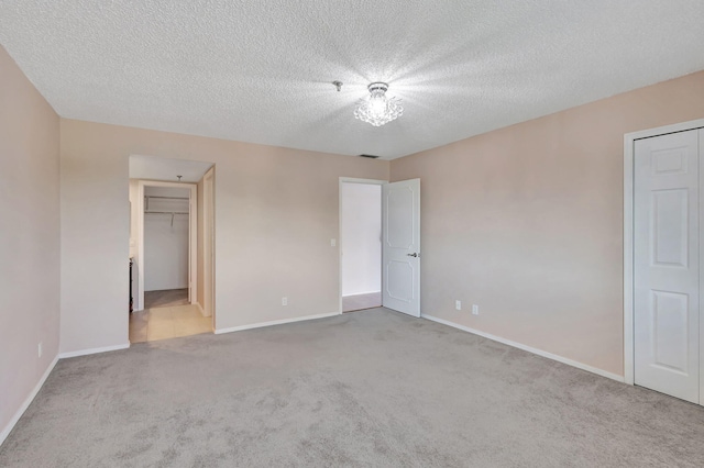 unfurnished bedroom with light carpet, a textured ceiling, and a closet