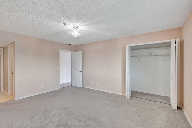 unfurnished bedroom featuring a textured ceiling, a closet, and light carpet