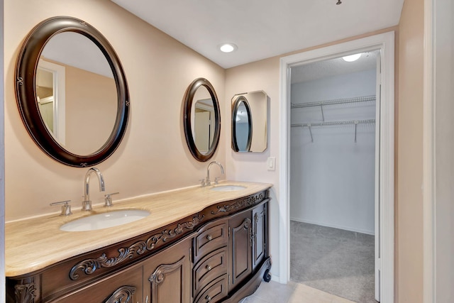 full bathroom with double vanity, a walk in closet, and a sink