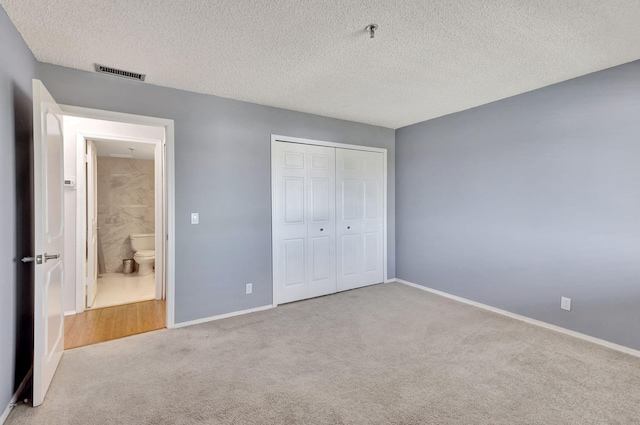 unfurnished bedroom with a closet, light colored carpet, and a textured ceiling