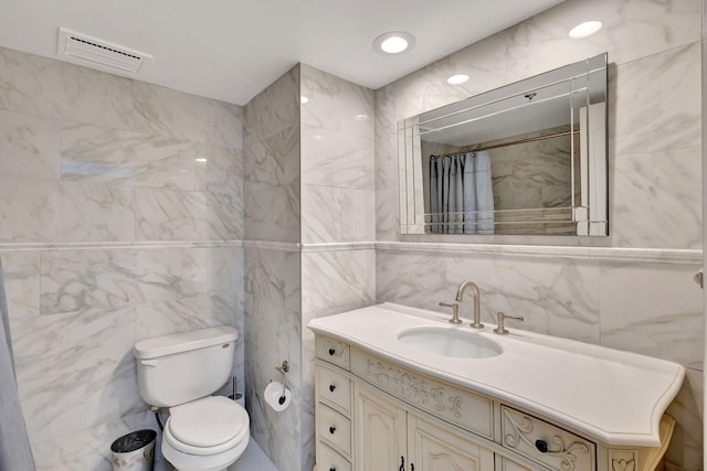 bathroom with tile walls, vanity, and toilet