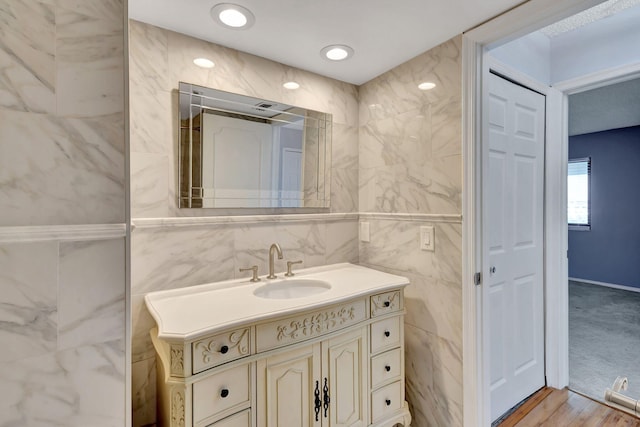 bathroom featuring wood-type flooring, vanity, and tile walls