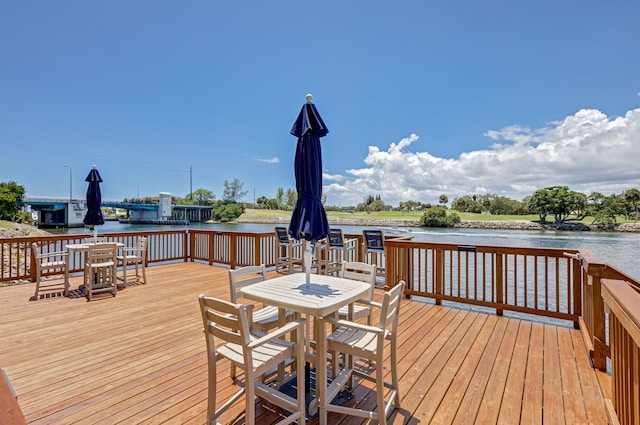 deck with outdoor dining space and a water view