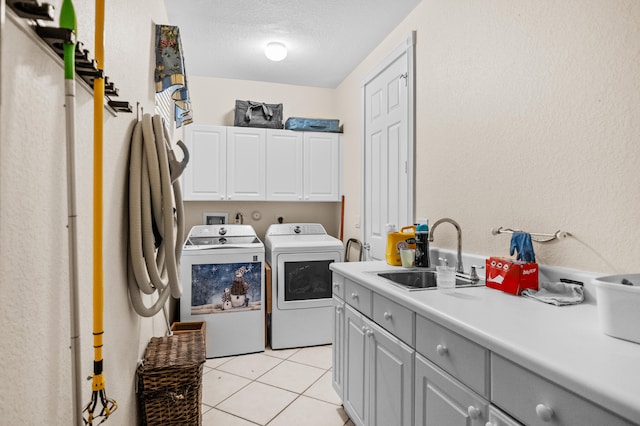 clothes washing area featuring light tile patterned flooring, washing machine and clothes dryer, sink, cabinets, and a textured ceiling