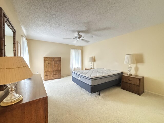 carpeted bedroom featuring ceiling fan and a textured ceiling