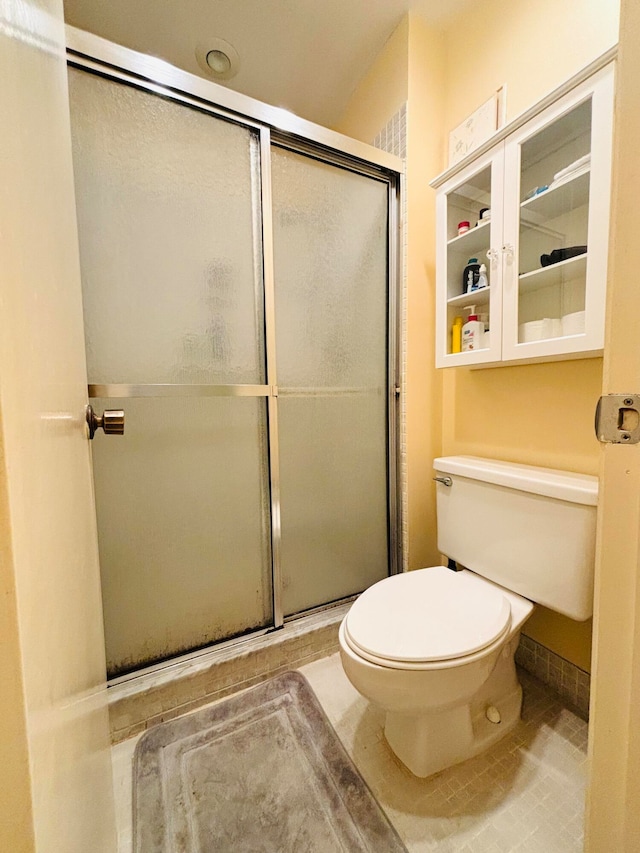 bathroom with tile patterned floors, an enclosed shower, and toilet