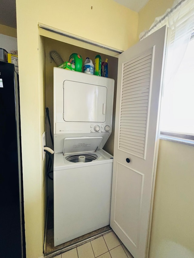 washroom featuring light tile patterned floors and stacked washing maching and dryer