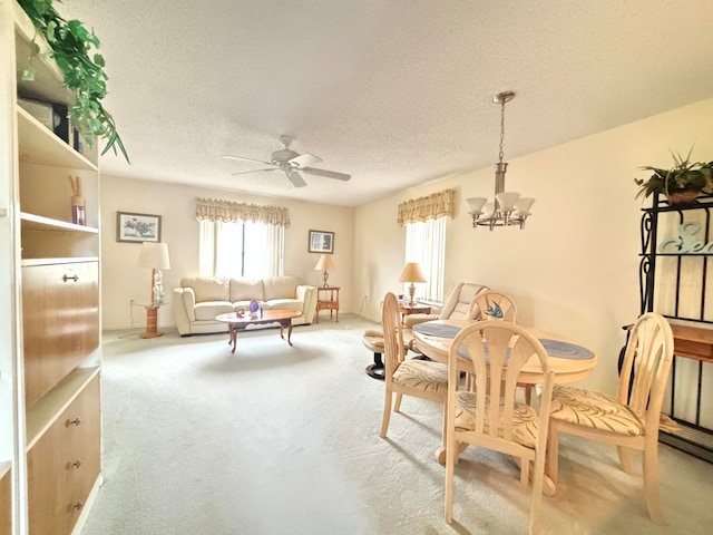 dining area featuring carpet flooring, a textured ceiling, and ceiling fan with notable chandelier