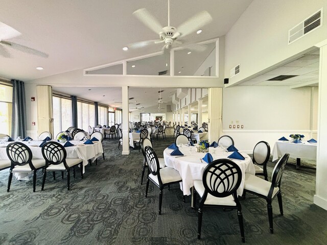 carpeted dining space with ceiling fan and lofted ceiling