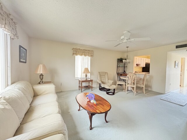 living room featuring a textured ceiling, light colored carpet, plenty of natural light, and ceiling fan