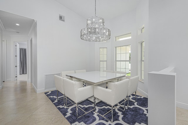 dining area with a chandelier, a high ceiling, and ornamental molding