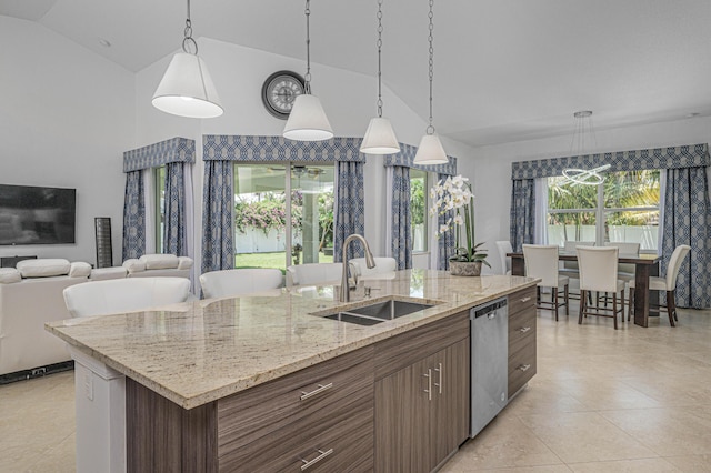 kitchen with a center island with sink, stainless steel dishwasher, sink, and a wealth of natural light