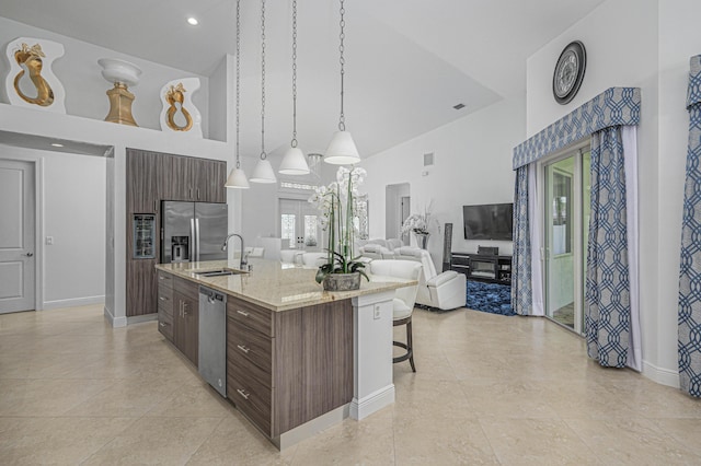 kitchen featuring dark brown cabinets, a center island with sink, high vaulted ceiling, and appliances with stainless steel finishes