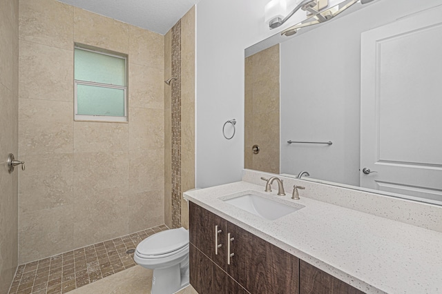 bathroom featuring tiled shower, vanity, and toilet