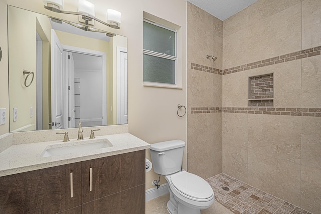 bathroom with tiled shower, vanity, and toilet