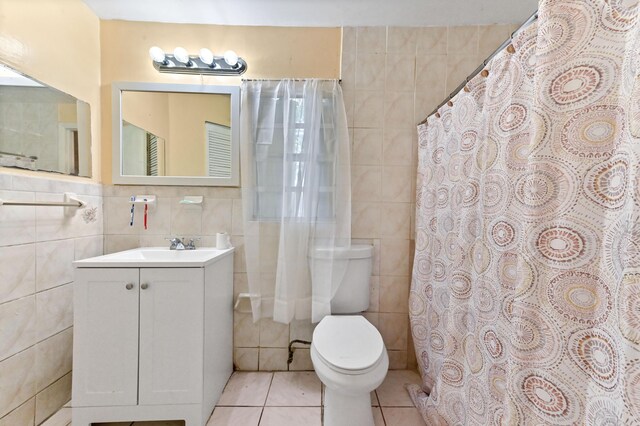 full bathroom with toilet, tile patterned flooring, tile walls, and vanity