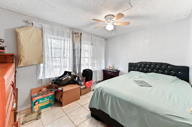 bedroom with a ceiling fan, a textured ceiling, and light tile patterned floors