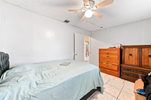 bedroom with visible vents, ceiling fan, a textured ceiling, and light tile patterned floors