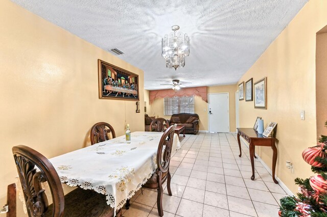 dining space with light tile patterned floors, visible vents, a textured ceiling, and ceiling fan with notable chandelier