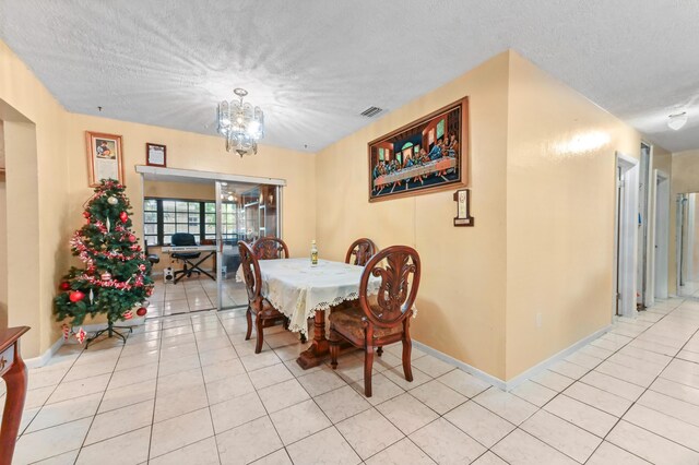 dining space featuring visible vents, a notable chandelier, a textured ceiling, and light tile patterned floors