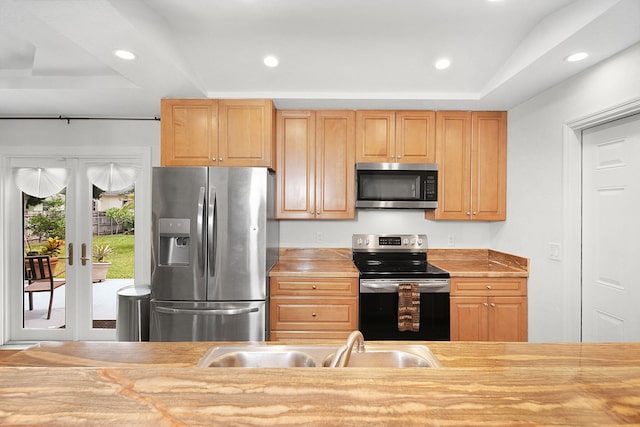 kitchen featuring french doors, a tray ceiling, stainless steel appliances, and sink