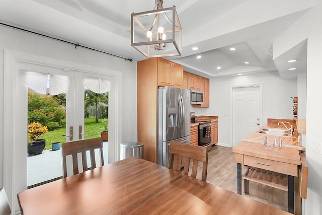 dining space featuring light hardwood / wood-style flooring, lofted ceiling, a chandelier, and sink