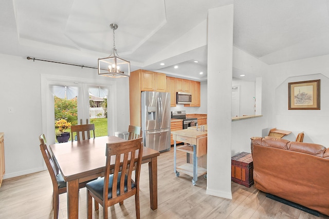 dining area featuring a raised ceiling, light hardwood / wood-style floors, a notable chandelier, and french doors