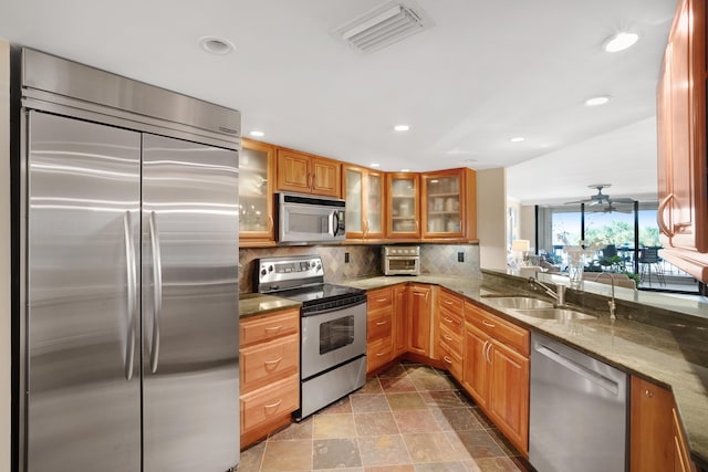 kitchen featuring dark stone counters, sink, ceiling fan, tasteful backsplash, and stainless steel appliances