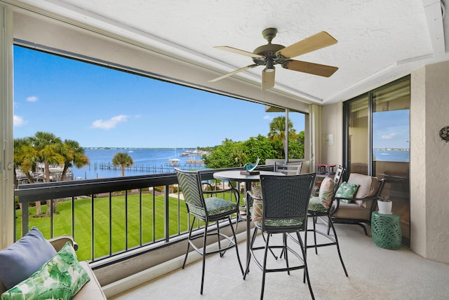 sunroom / solarium with ceiling fan and a water view