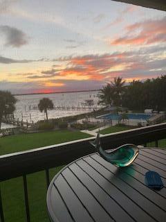 balcony at dusk featuring a water view