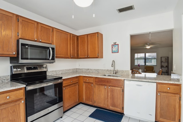 kitchen featuring sink, light tile patterned floors, appliances with stainless steel finishes, light stone countertops, and ceiling fan