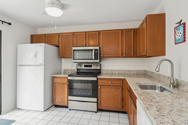 kitchen with ceiling fan, appliances with stainless steel finishes, light stone countertops, light tile patterned floors, and sink