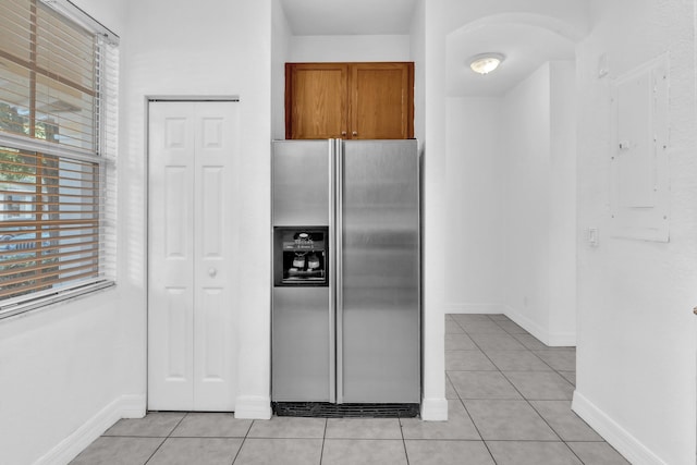 kitchen with stainless steel fridge, electric panel, and light tile patterned floors