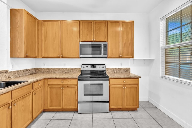 kitchen with sink, appliances with stainless steel finishes, light stone counters, and light tile patterned floors