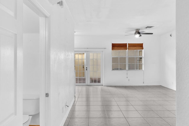 tiled spare room featuring ceiling fan and french doors