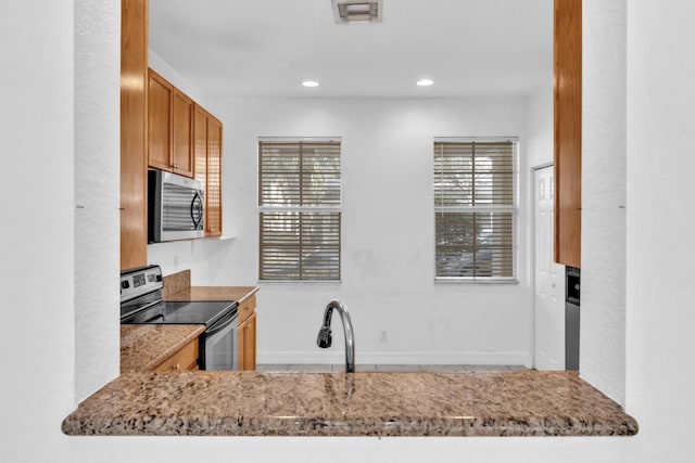 kitchen with sink, black electric range oven, and light stone countertops