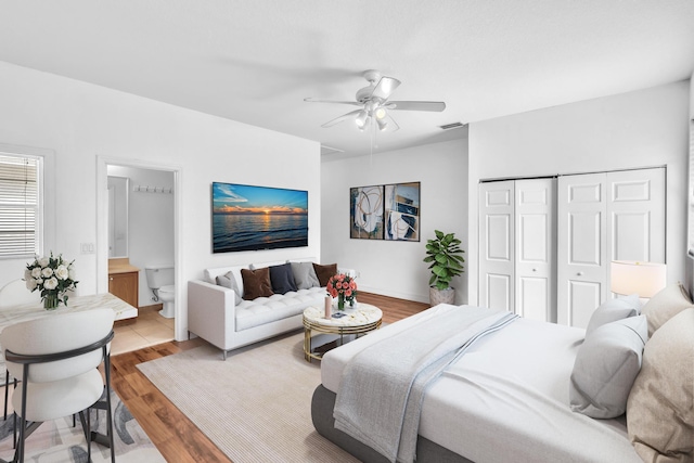 bedroom with a closet, ceiling fan, light hardwood / wood-style floors, and connected bathroom