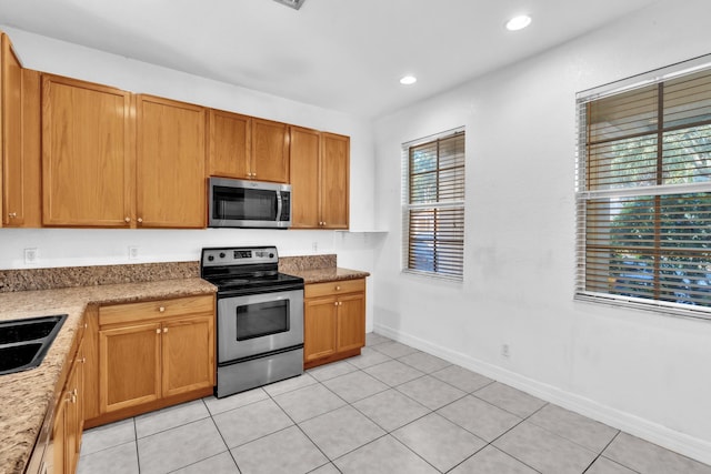 kitchen with appliances with stainless steel finishes, light tile patterned floors, and sink