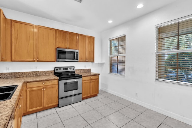 kitchen featuring light tile patterned floors, light stone countertops, sink, and appliances with stainless steel finishes