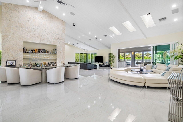 living room featuring bar area, beam ceiling, and high vaulted ceiling