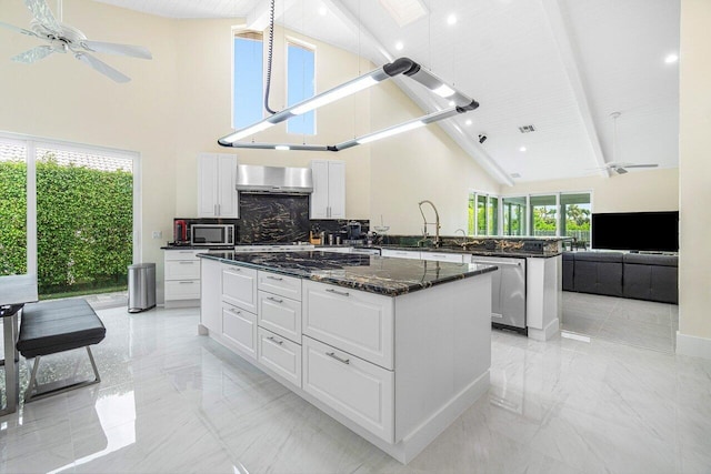 kitchen with beamed ceiling, a kitchen island, high vaulted ceiling, white cabinetry, and appliances with stainless steel finishes