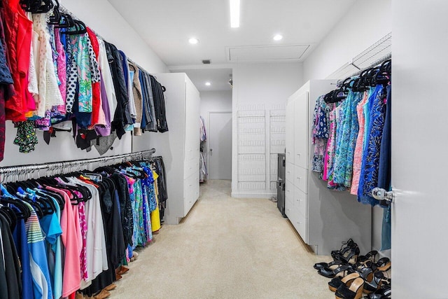 walk in closet with light carpet